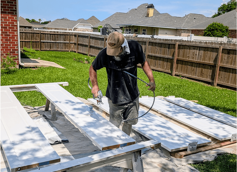 Man spray painting wooden boards outdoors.