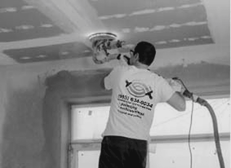 Person sanding ceiling with power tool.
