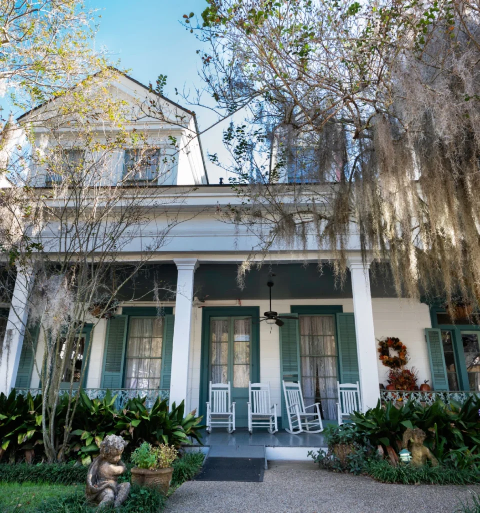 Southern-style house with rocking chairs and trees.